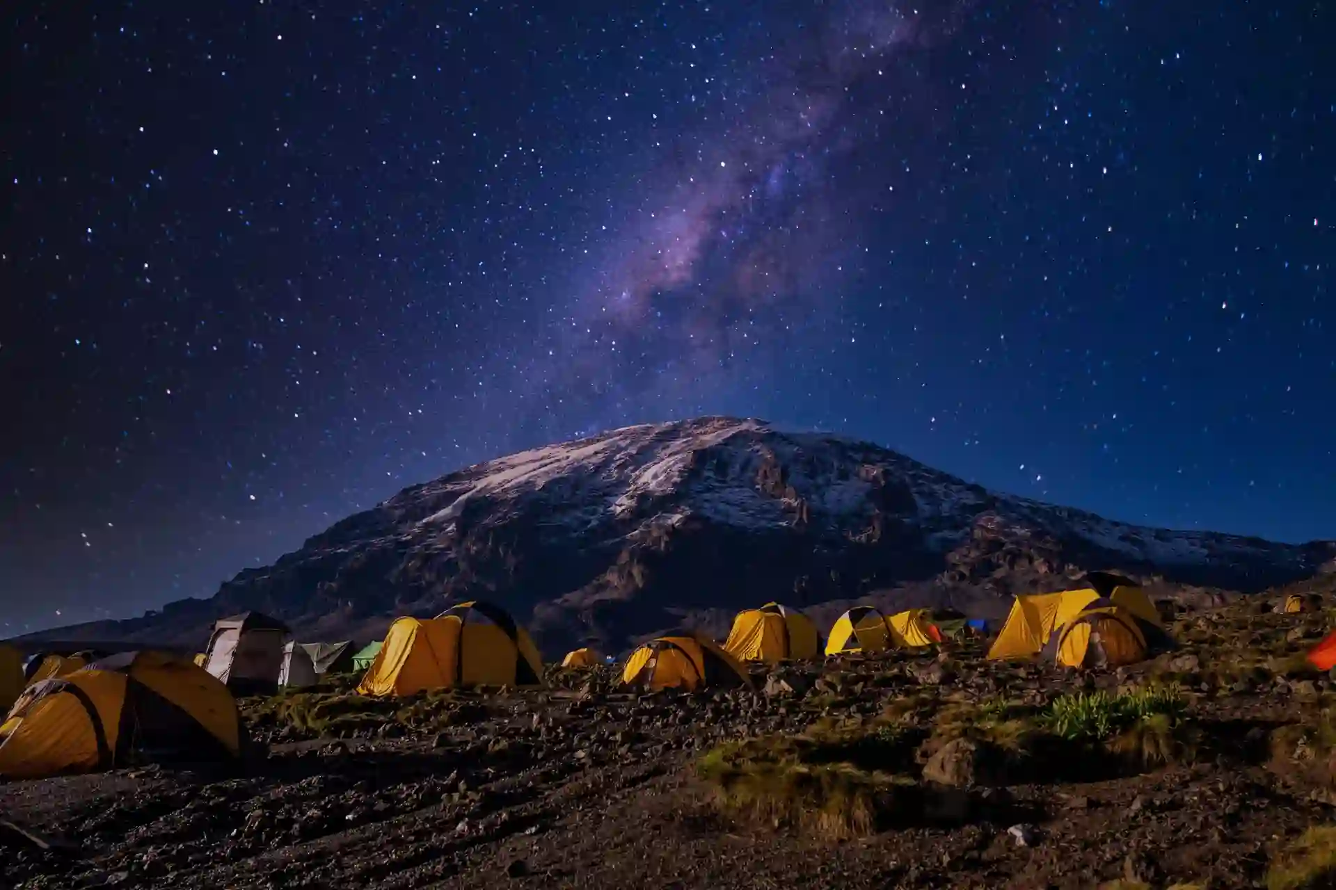 A breathtaking view of yellow tents set against the majestic backdrop of Mount Kilimanjaro in Kilimanjaro National Park.