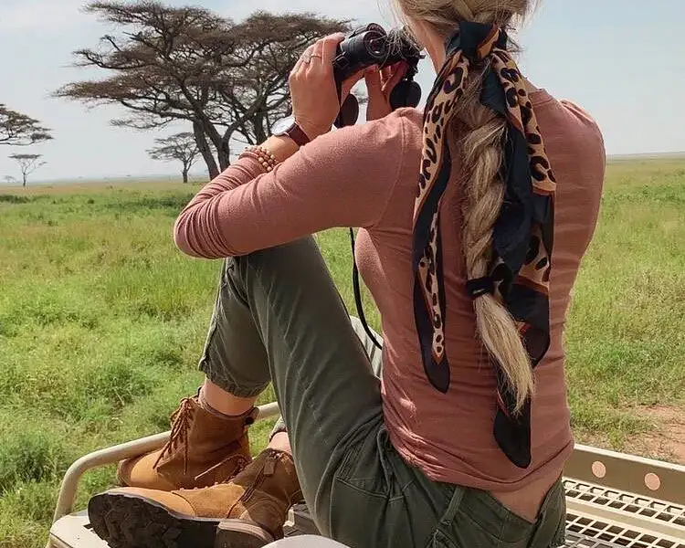A group of tourists wearing safari hats observing wildlife in Tanzania during high season.